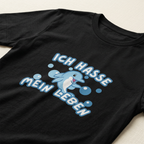 Detailaufnahme des Delfin-Motivs mit Spruch „Ich hasse mein Leben" auf schwarzem Baumwoll-T-Shirt